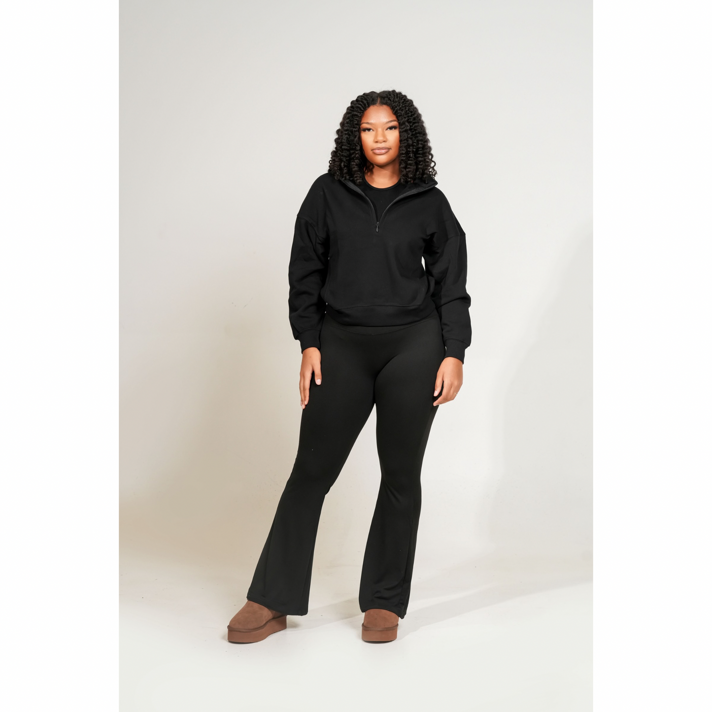 Person wearing a black hoodie and black pants on a white background. FLEECE HIGH NECK HALF ZIP SWEATSHIRT