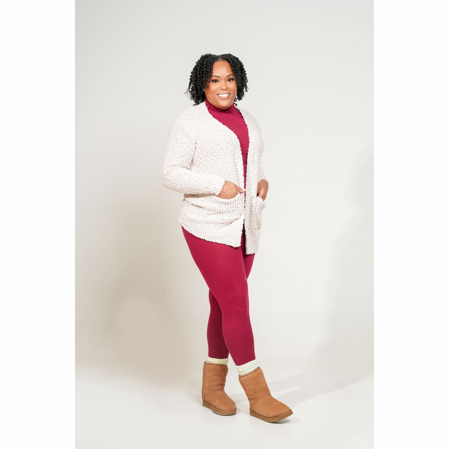 Woman wearing a white cardigan, and brown boots on a white background. LONG SLEEVE POPCORN SWEATER CARDIGAN WITH POCKETS. sand Beige