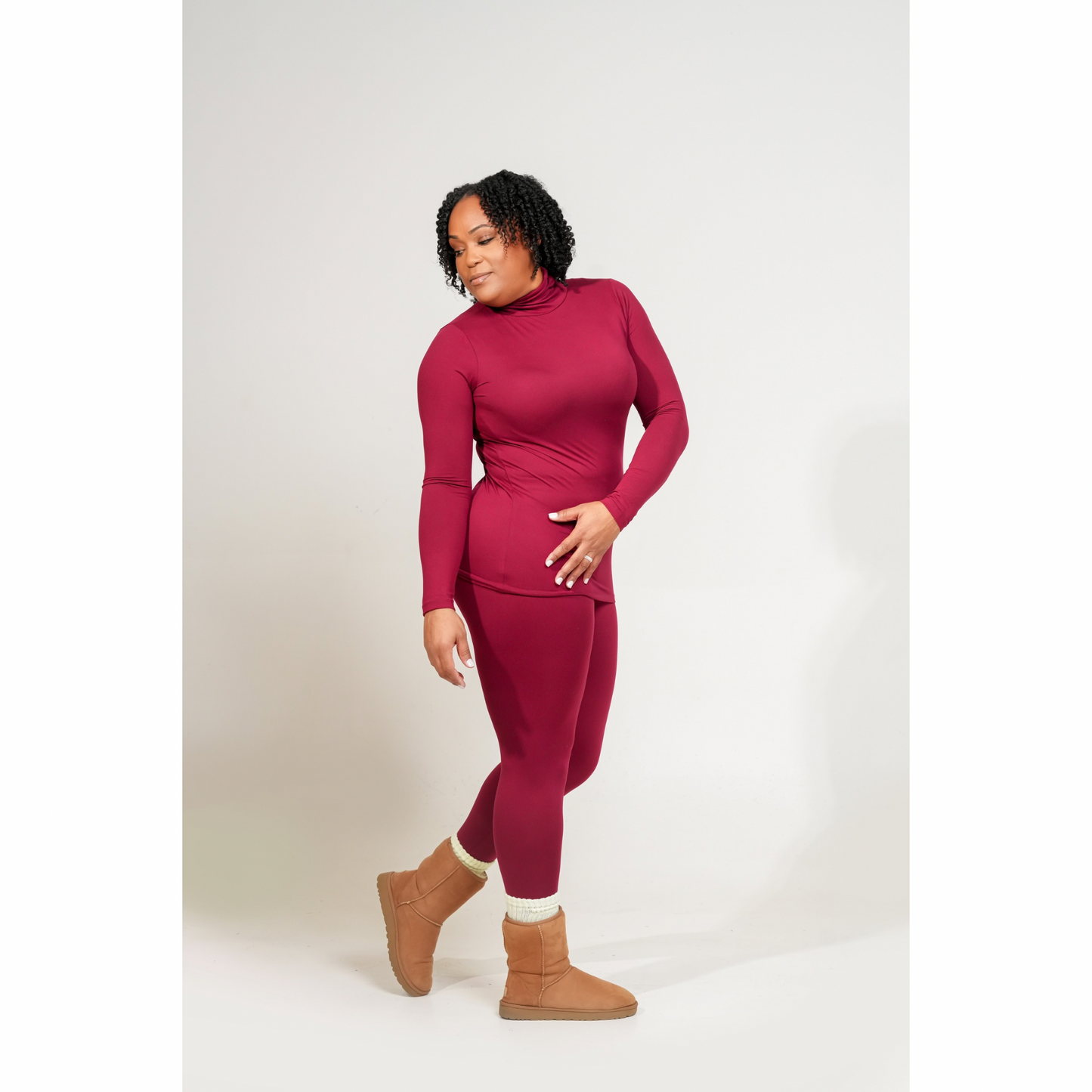 Woman wearing a MICROFIBER MOCK NECK TOP & LEGGINGS SET
outfit with brown boots on a white background. CABERNET