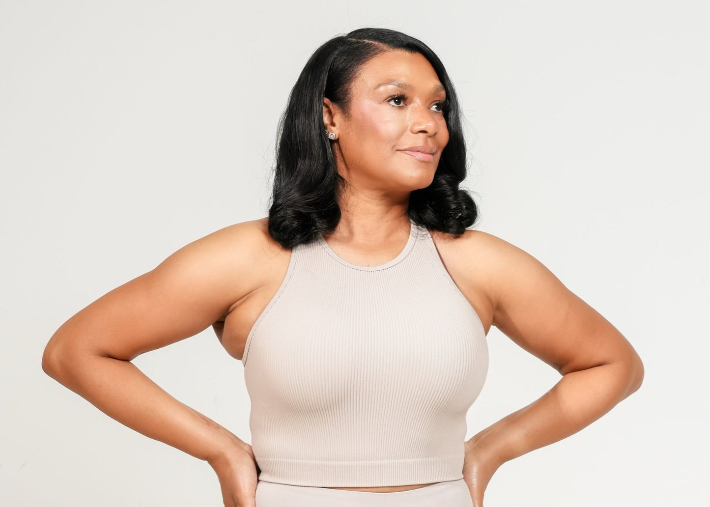 Woman wearing a beige athletic outfit on a white background. Ribbed Seamless High-Neck Cropped Tank is designed for women who want comfort, support, and ease—without the bulk.