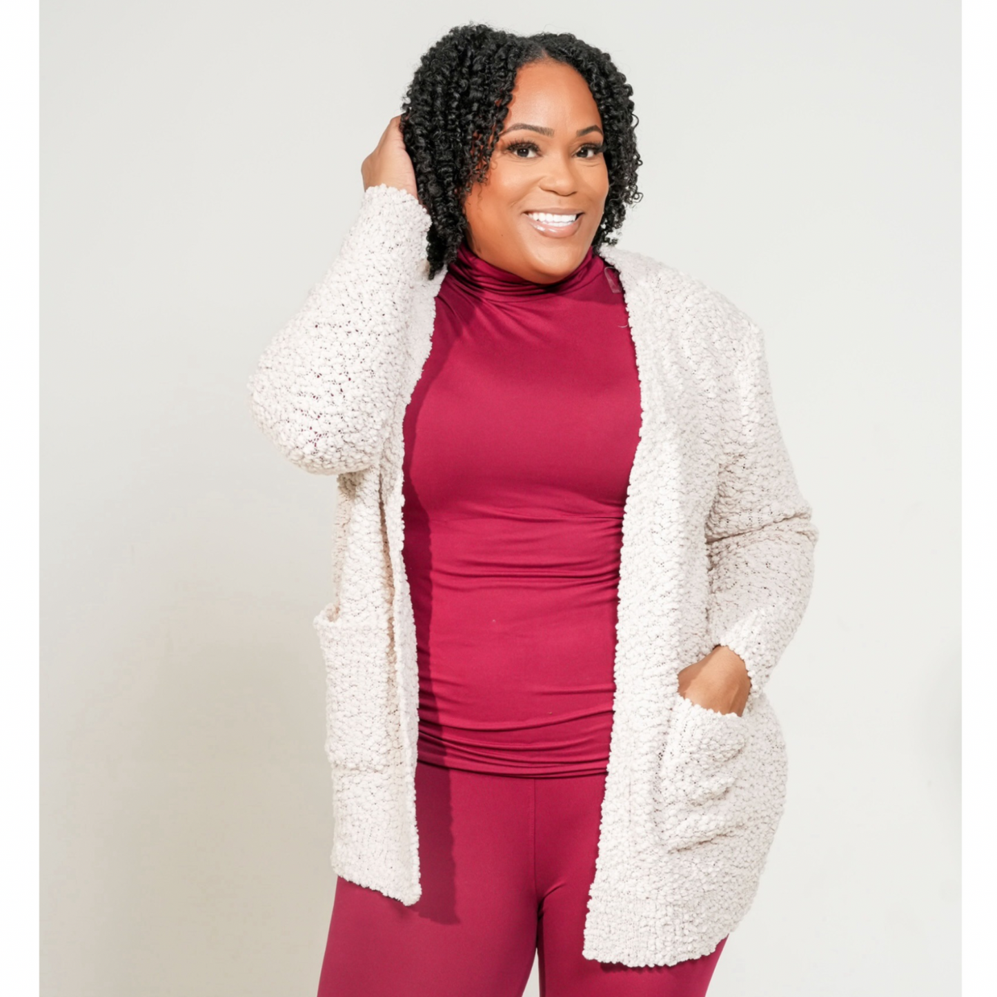Woman wearing a white cardigan over a red outfit against a plain background. LONG SLEEVE POPCORN SWEATER CARDIGAN WITH POCKETS