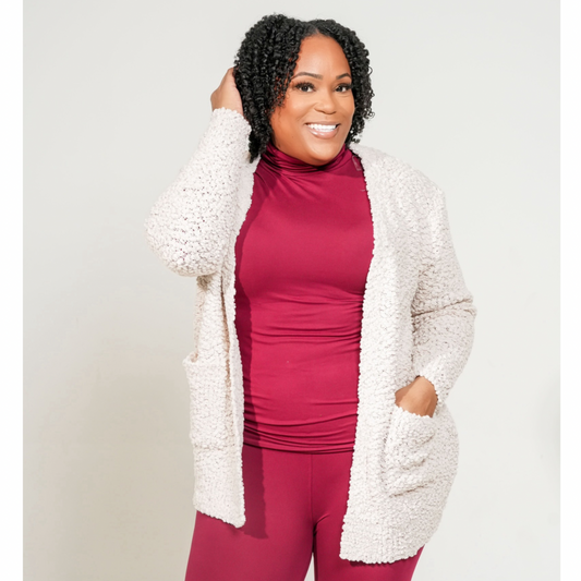 Woman wearing a white cardigan over a red outfit against a plain background. LONG SLEEVE POPCORN SWEATER CARDIGAN WITH POCKETS