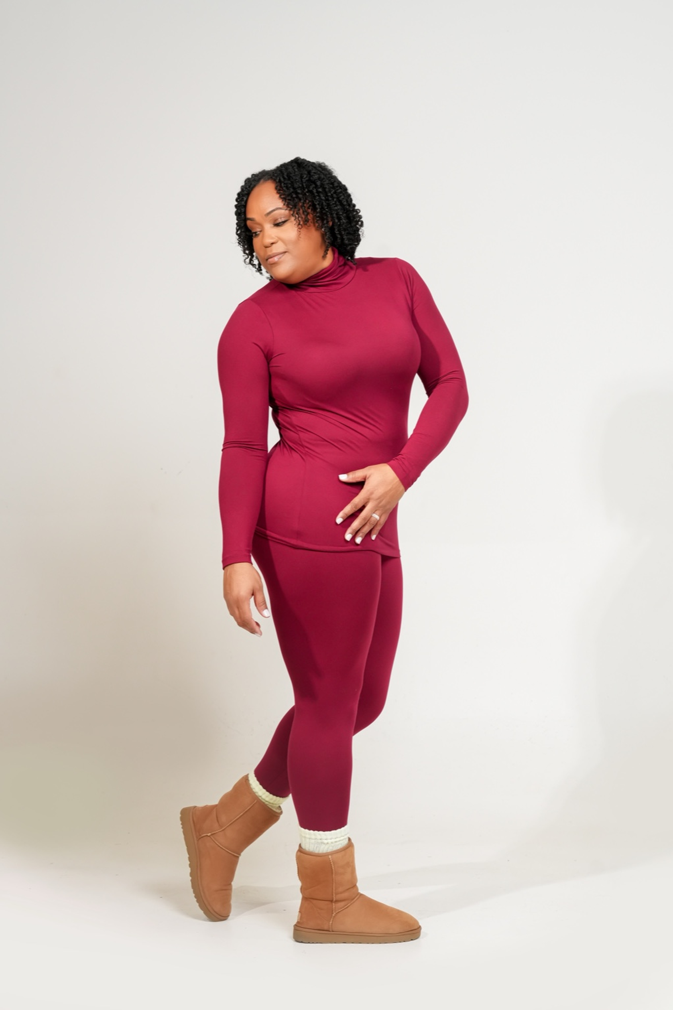 Woman wearing a MICROFIBER MOCK NECK TOP & LEGGINGS SET
outfit with brown boots on a white background. CABERNET
